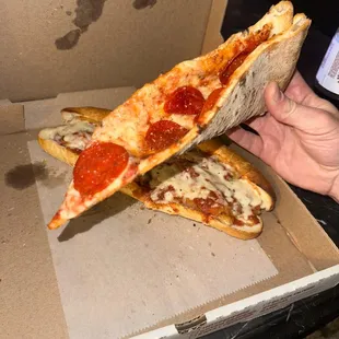 a hand holding a slice of pizza