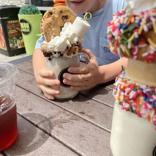 a young boy sitting at a table with an ice cream sundae