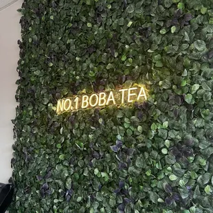 a wall of plants and a neon sign