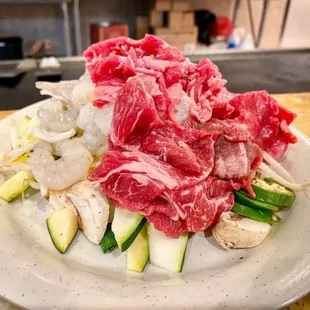 a plate of raw meat and vegetables