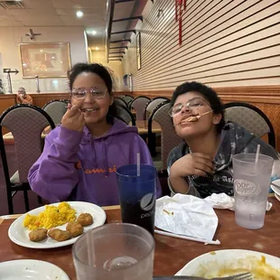 two people sitting at a table with plates of food
