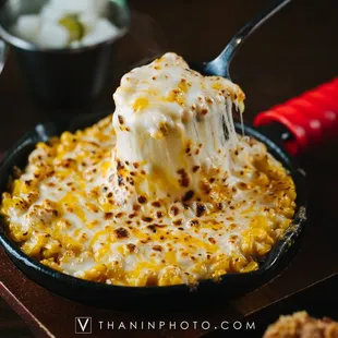  a fork lifting a serving of macaroni and cheese
