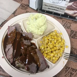 Beef brisket dinner with potato salad and corn