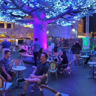 people sitting at tables under a tree