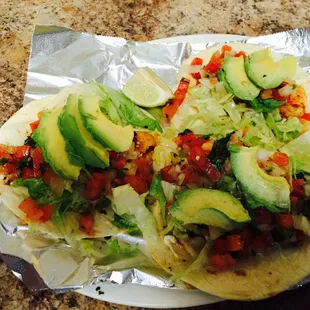 a taco with avocado, tomatoes and lettuce