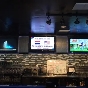 two televisions above a bar
