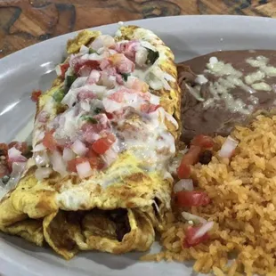 Mexican Omelette. Topped with cheese dip and pico de gallo also served with rice and beans.