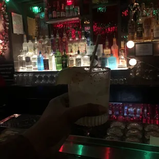 a person holding a drink in front of a bar