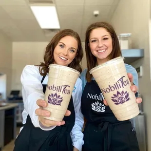 two women in aprons holding cups of coffee
