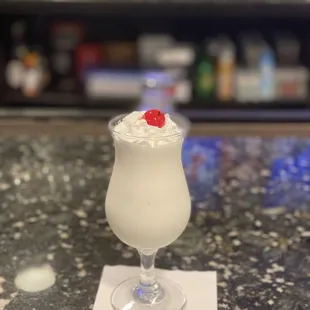 a white cocktail with a cherry on top