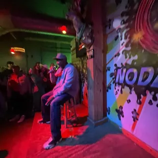a man sitting on a stool in front of a colorful wall