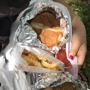 a person holding a hamburger and french fries
