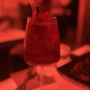 a red cocktail in a glass on a table