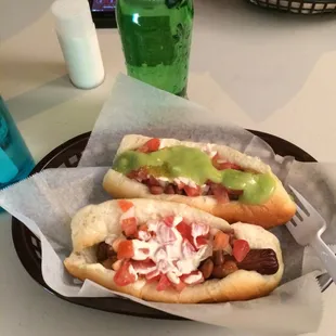 Nogales dog with salsa verde and guac sauce. The first dog just has the traditional toppings: beans, tomato, onion, and mayo.