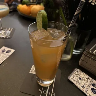 a cocktail in a tall glass with a lime garnish