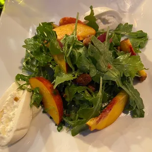 Peach, Burrata Salad. An Arugula Salad with Honey Roasted Walnuts, Peach Wedges and Burrata Cheese, drizzled in Olive Oil.