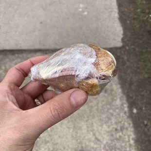 a person holding a sandwich wrapped in plastic