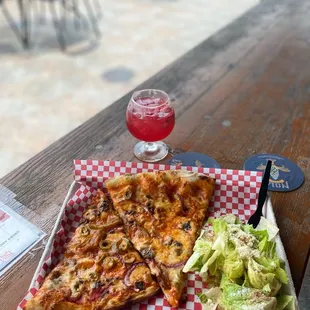 a slice of pizza and salad on a picnic table