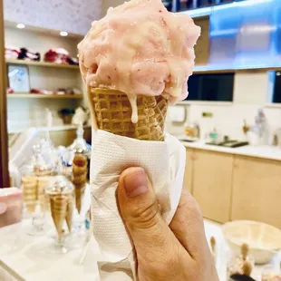 Strawberry lychee ice cream with condensed milk, on a sugar cone