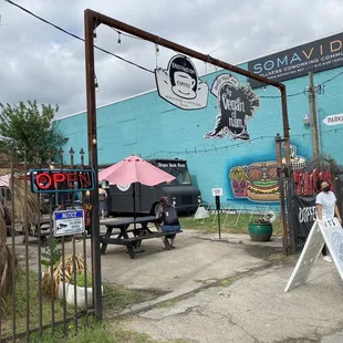 a blue building with a sign and a pink umbrella