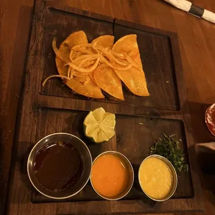 Cheesy Birria Tacos: Three corn tortillas filled with braised short rib, melted cheese, with onion, cilantro, habanero sauce and consommé.