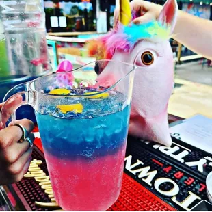a unicorn drinking a blue and pink drink