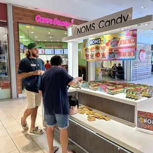 a man and a woman standing in front of a display of donuts