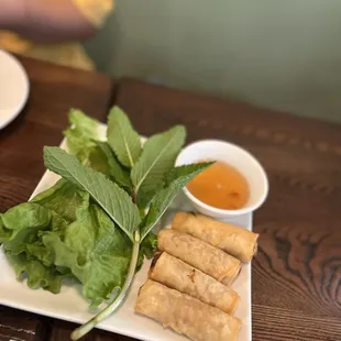a plate of vegetable spring rolls and dipping sauce