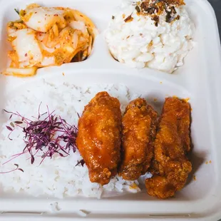 a tray of food with rice, meat, and vegetables