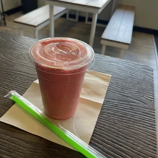 a smoothie in a plastic cup with a green straw