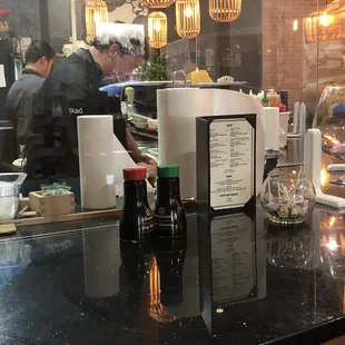 Bare hands touching sushi rolls.