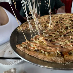 a person taking a slice of pizza