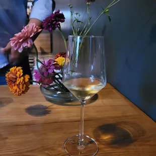a glass of wine and a vase of flowers