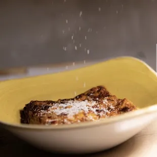 a plate of food being sprinkled with powdered sugar