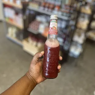 a hand holding a bottle of soda