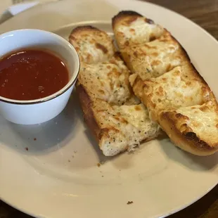 two pieces of bread and a bowl of tomato sauce