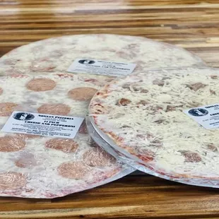 three uncooked pizzas