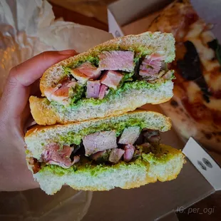 a hand holding a half eaten sandwich