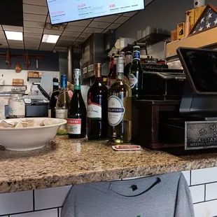 a counter with a bowl of food and bottles of wine