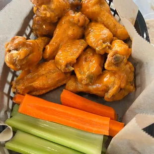a basket of chicken wings, carrots, celery, and celery sticks
