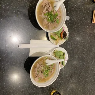 two bowls of soup and a bottle of beer