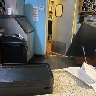 a kitchen counter with a trash can and a trash can