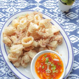 a plate of fried squid with a bowl of dipping sauce