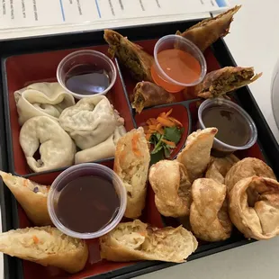 a tray of food with dipping sauces