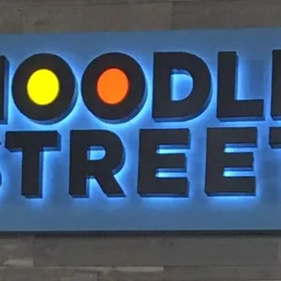 a neon sign for noodle street