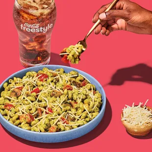 a hand holding a fork and a bowl of pasta