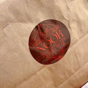 a brown paper bag with a red sticker on it