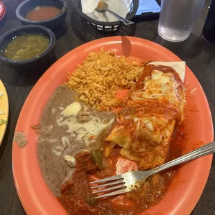 Smothered red pork burrito with a side of rice and bean