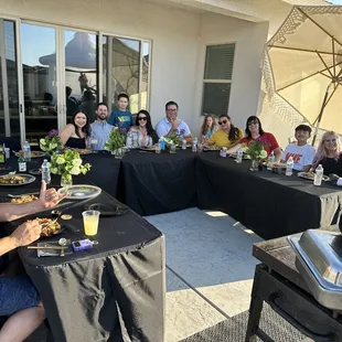 a group of people sitting at a table with food and drinks