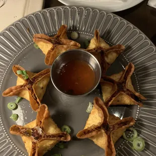 a plate of wontons with dipping sauce